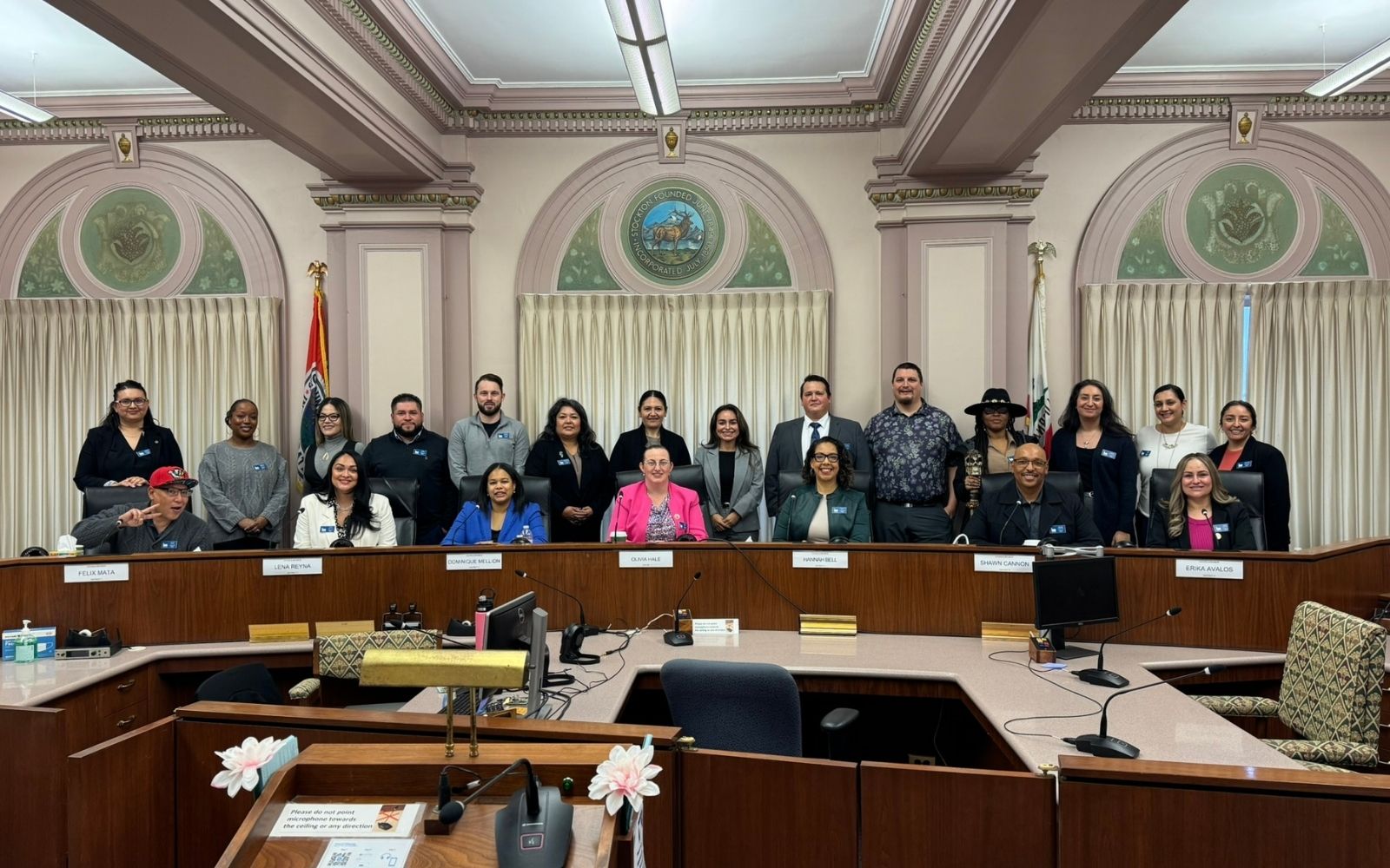 Group of adults standing around a council chamber