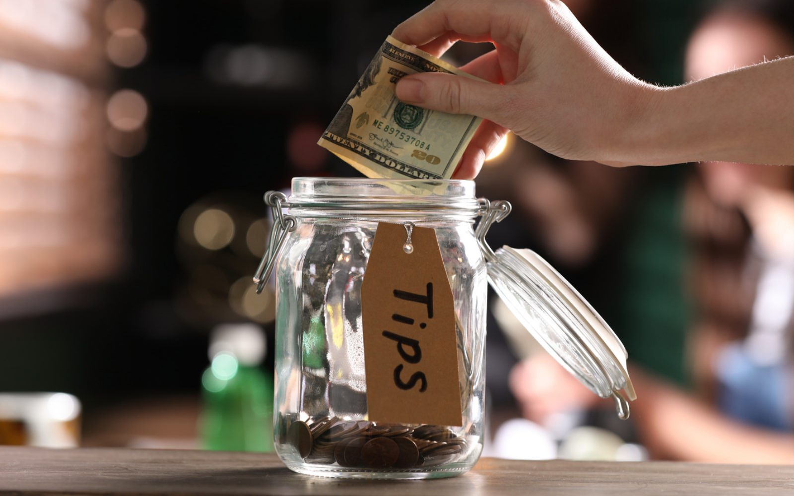 A person putting money into a tip jar