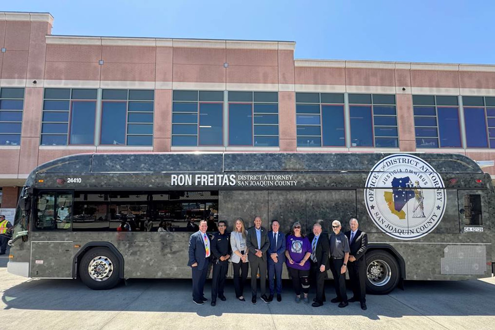 several people posing next to a city bus