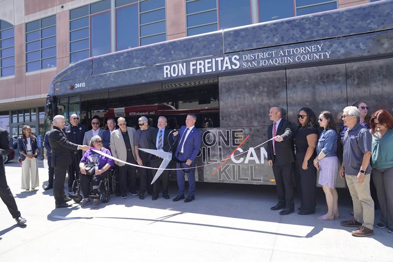Ron Freitas cutting a ribbon next to a city bus
