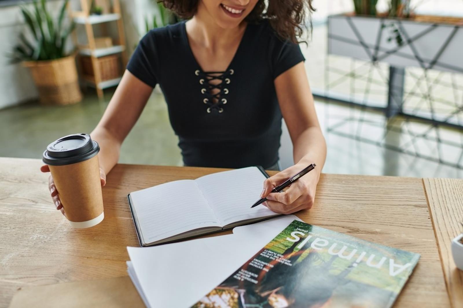 a woman smiling while writing in a notebook