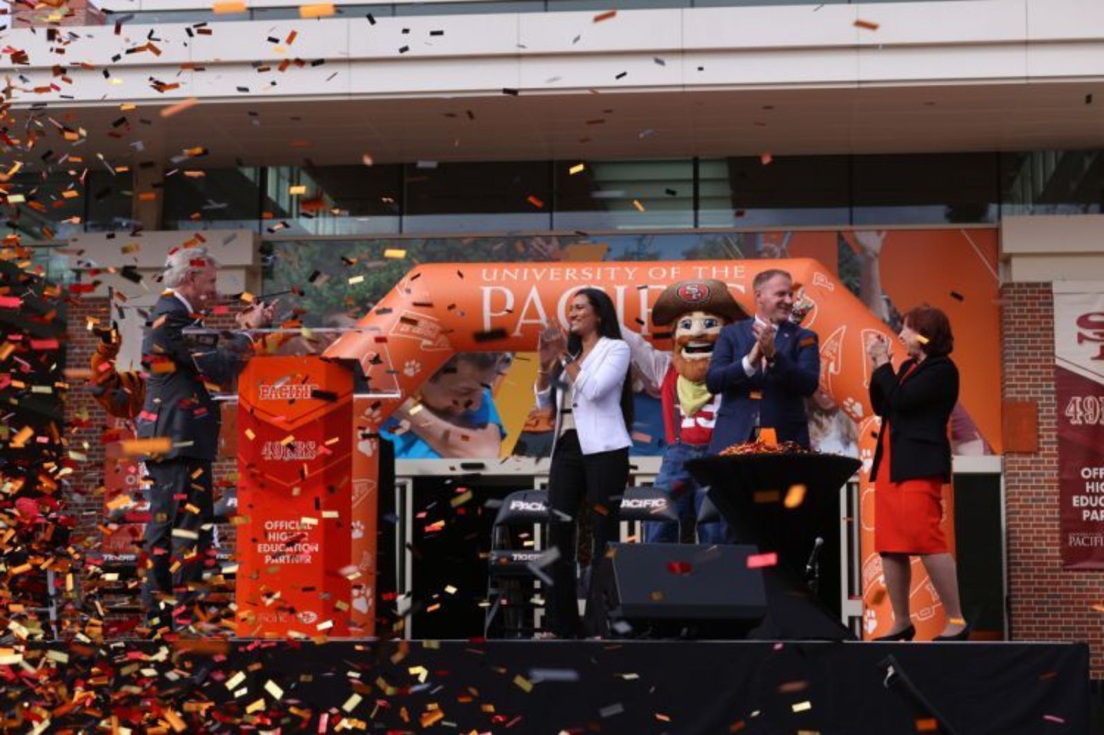 Confetti falling over stage with speakers beside large orange inflatable arch